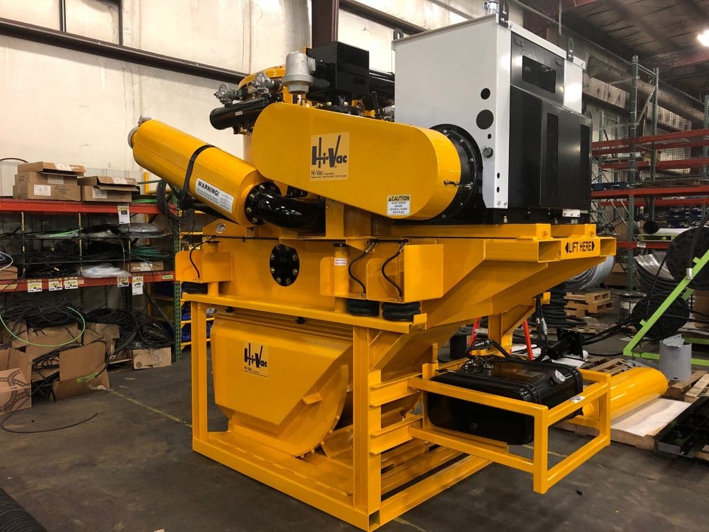 Yellow skid-mounted Hi‑Vac industrial vacuum system with blower, tank and controls inside a manufacturing warehouse