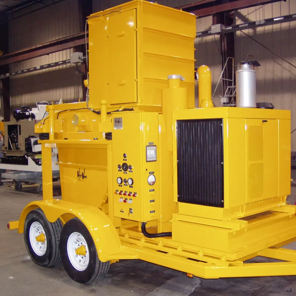 Bright yellow Hi‑Vac industrial vacuum trailer with dual axles, control panel, radiator and exhaust, inside fabrication shop