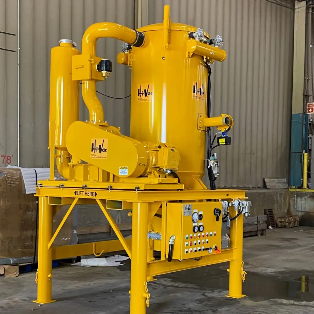 Bright yellow Hi-Vac industrial vacuum skid with large cyclone tanks, inlet piping and control panel in factory setting