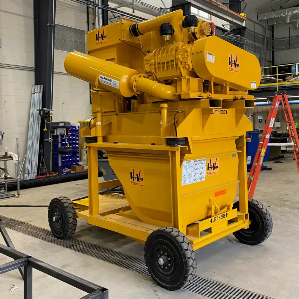 Yellow Hi-Vac portable industrial vacuum hopper and blower assembly on wheeled chassis inside a manufacturing shop.